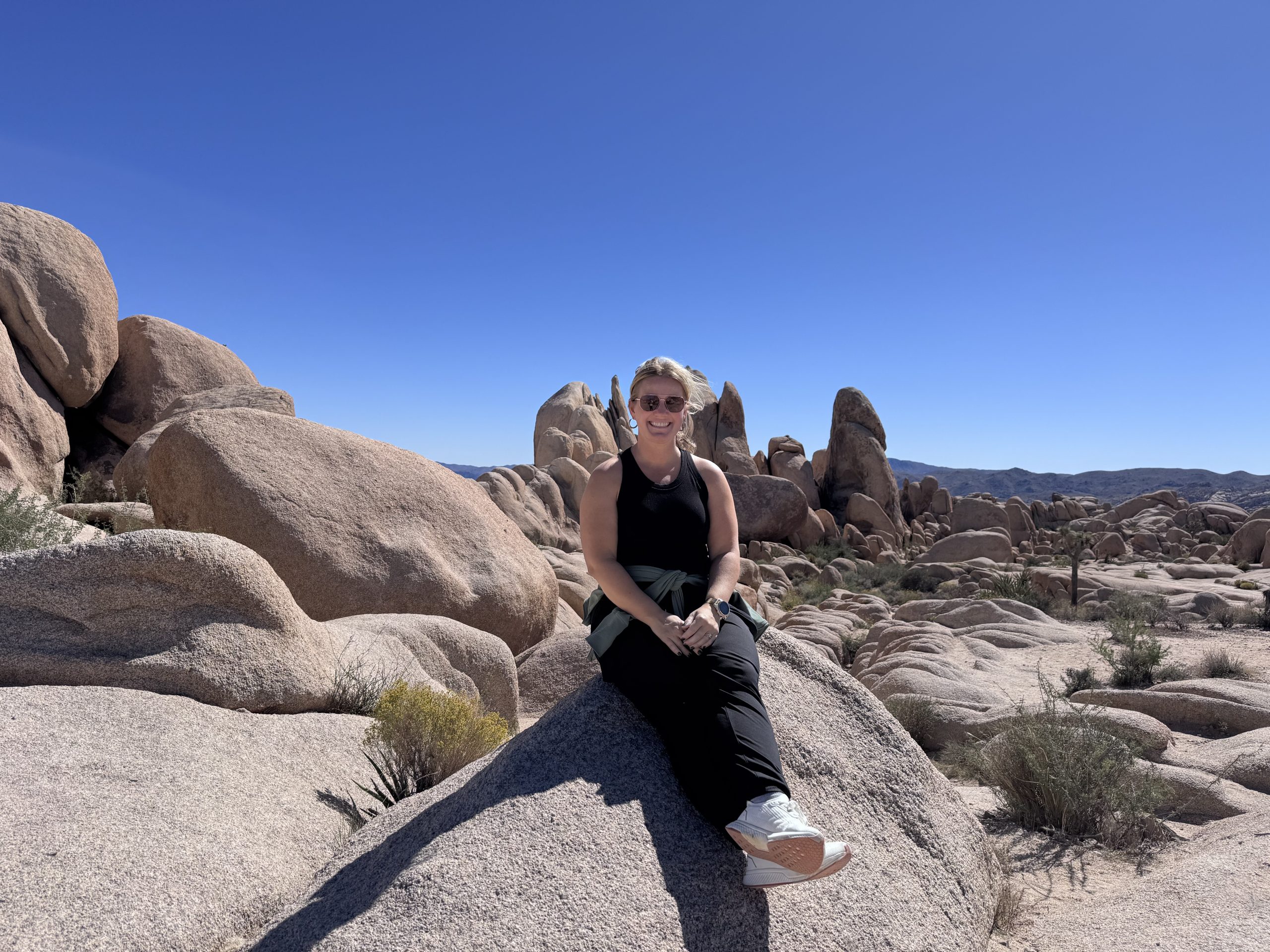 IMG_6261 Anna Miller sitting on a boulder in a desert landscape while hiking